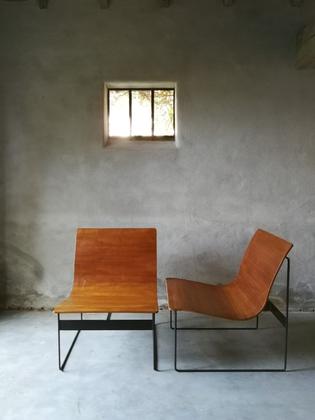 A pair of wooden and black metal lounge chairs